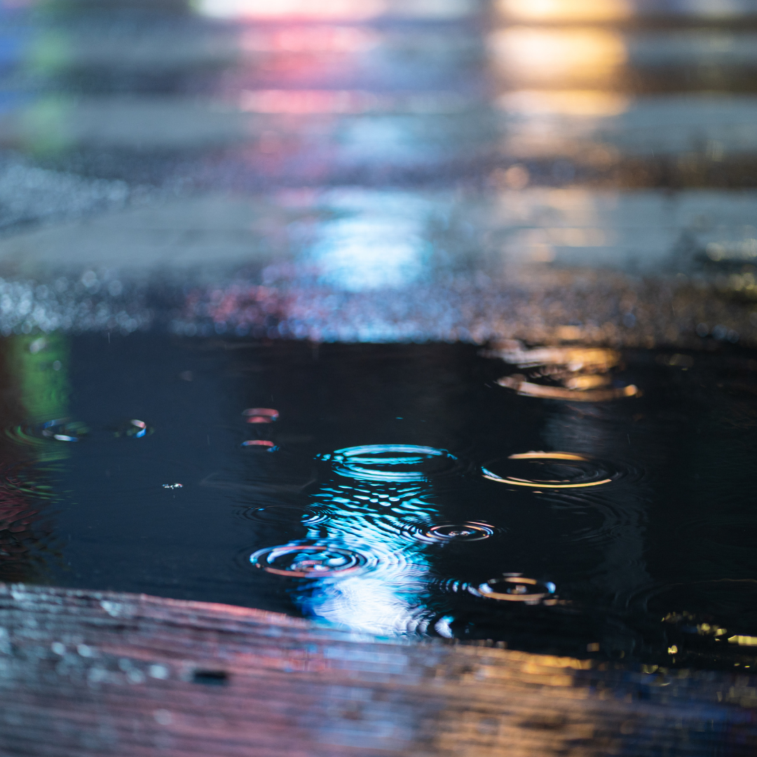 vivi & vela midnight inspiration - city lights reflecting on wet pavement under a rainy night sky