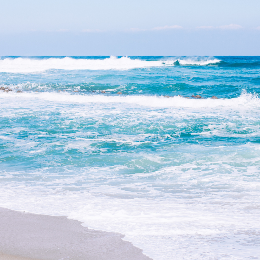 vivi & vela sea song inspiration - gentle waves crashing along a sandy shoreline under a blue sky